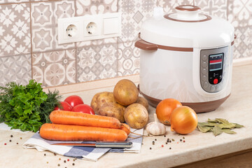 Modern, light multi cooker and raw products on table in kitchen. Cooking a healthy, vegetarian dish in a multi cooker, slow cooker.