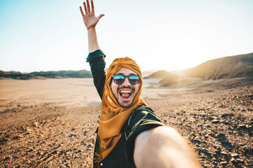 Happy traveler with backpack taking selfie picture with smart mobile phone outdoors - Cheerful guy...