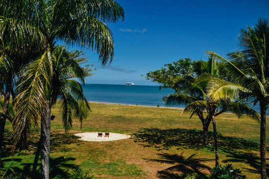 Foto de un paisaje paradisiaco con dos tumbonas en la playa rodeadas por palmeras y el mar de Nadi, Fiji.