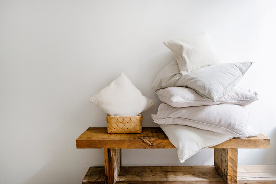Wicker laundry basket with small cushion close to pillow in white pillowcases