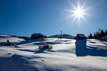 Landscape with an isolated old house on the slope of a mountain in a rural area covered with snow -...