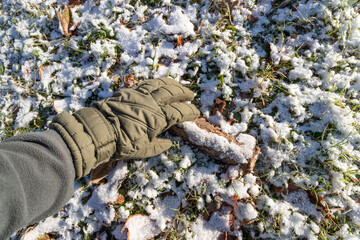 Ein Stück Holz im Winter bei Frost mit Handschuhe aufheben.