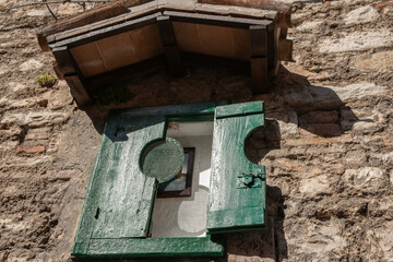Green doors of old food safe high on stone wall from low angle