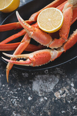 Boiled legs and claws of opilio or snow crab with lemon, vertical shot, closeup, selective focus