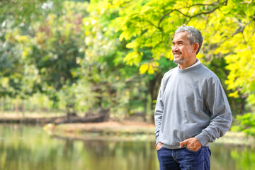 portrait happy asian senior man relaxing by the pond in the public park - obrazy, fototapety, plakaty