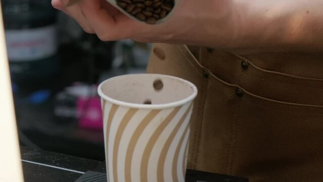 Pouring roasted coffee beans into the cup for measuring