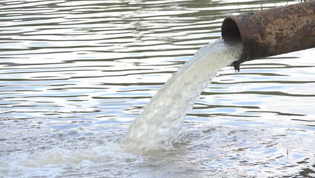 Waste water discharge from rusty pipe in the polluted lake