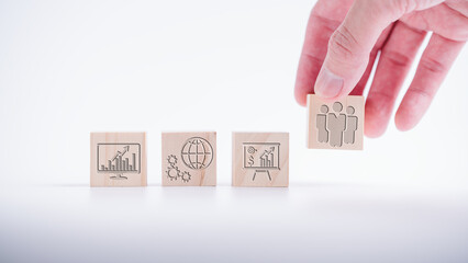 Team work to be success concept, wooden blocks with icons and man hand putting people icon which is the most important and powerful to drive the organisation to be successful