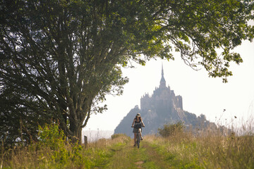 cyclotouriste femme de face, devant le Mont Saint Michel en normandie
