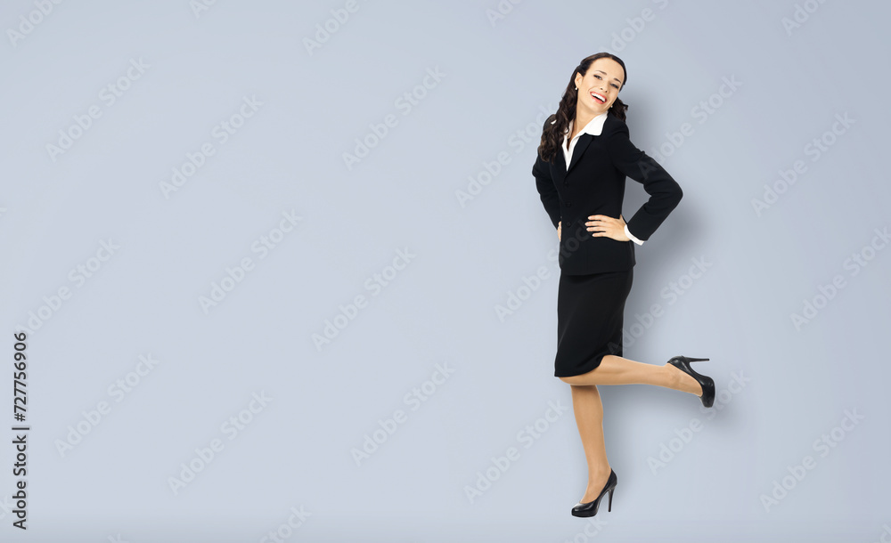 Wall mural Full body length of happy excited smiling businesswoman with hands on hips, copy space for text. Confident woman in black suit standing dancing isolated on grey gray background. Business concept.