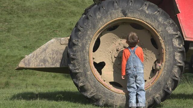 Small child inspecting the big tractor tire