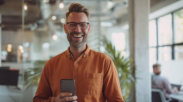 M&auml;nnlicher Arbeiter im B&uuml;ro mit Handy in der Hand