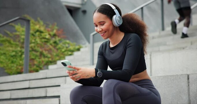 Fitness, smartphone and happy woman on headphones outdoor, typing in city or streaming radio sound by steps. Phone, sports and person listening to music on mobile app, audio or scroll on social media