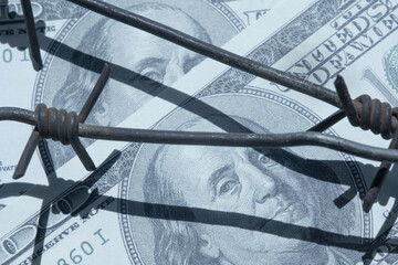 Economic confrontation and warfare, sanctions and embargo. Barbed wire against US Dollar bill. Horizontal image.