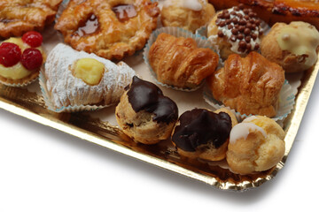 Traditional assortment of italian pastries on golden tray. Cannoli, Babà, cream puffs, small pies with jam, mini tart with cream and fruits and apple pie