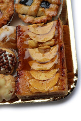 Traditional assortment of italian pastries on golden tray. Cannoli, Babà, cream puffs, small pies with jam, mini tart with cream and fruits and apple pie