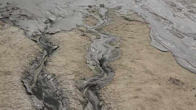 Liquid mud flowing in small creeks from muddy volcanoes