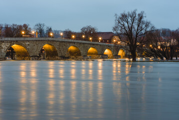 Fototapeta na wymiar Regensburg, Steinerne Brücke, im Dezember mit Hochwasser am Abend