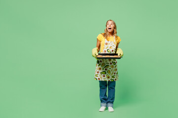 Full body amazed young housewife housekeeper chef cook baker woman wears apron yellow t-shirt hold...