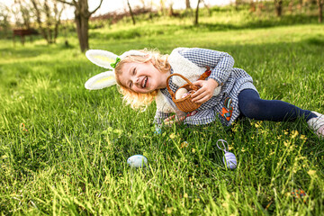 A girl fell on the grass laughing while hunting for Easter eggs. Easter Games