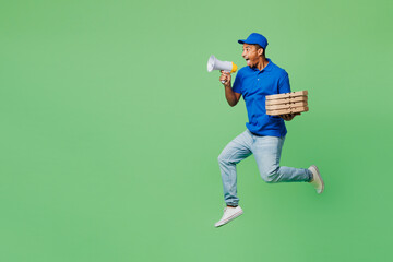 Delivery fun employee man wear blue cap t-shirt uniform workwear work as dealer courier jump high hold stack of pizza in flatbox scream in megaphone isolated on plain green background Service concept.