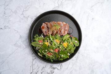 Salad with duck breast, arugula leaves, orange, crushed walnuts