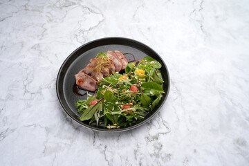 Salad with duck breast, arugula leaves, orange, crushed walnuts