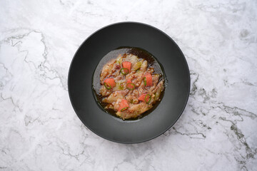 Spicy tom yum soup in a black plate