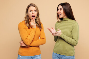 Young friend two women they wear orange green shirt casual clothes together tell secret gossip cover mouth with hand isolated on plain pastel light beige background studio portrait Lifestyle concept2