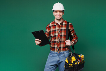Young cheerful employee laborer man wears red shirt hardhat hat work hold clipboard with paper...