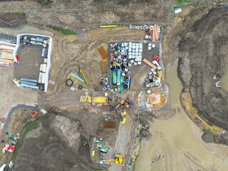 Drone top down view of parked up construction vehicles and materials seen on a new housing development in the UK.