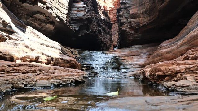 Small stream of water flowing in the narrow 'spider walk' in gorgeous Hancock Gorge in Karijini National Park, Western Australia. Hancock Gorge to Kermit pool pathway. Famous hiking adventures in WA