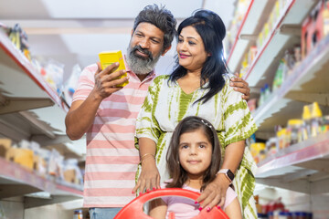 Indian family of three shopping for groceries at the supermarket. Buying grocery for home. couple...