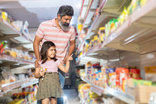 Happy indian father and daughter shopping for groceries at the supermarket.Little girl pointing at the products.
