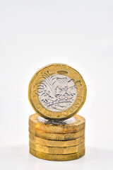 British one pound coin standing on top of a column of coins isolated on a plain white background. Finance concept.