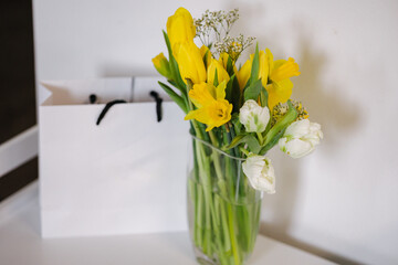 Little bouquet of beautiful yellow flowers. Daffodils in vase and present. Woman's day