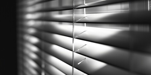 A black and white photo of a window with blinds. Can be used to create a modern and minimalist atmosphere in design projects