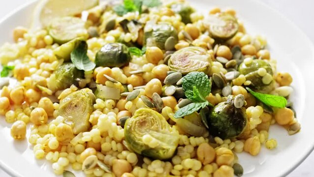 Vegetarian Tabbouleh Salad. Couscous brussels sprouts and chickpeas warm salad with pumpkin seeds. Healthy vegetarian diet food. Stock footage video 4k