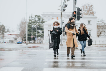 Young business professionals crossing the street on a snowy day outdoors.