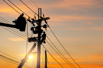 Silhouette of Electrician officer team climbs a pole and using a cable car to maintain a high...