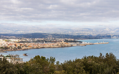 Fototapeta na wymiar View of Juan les Pins with the old city centre of Antibes and Port Vauban harbor in the background. Cote d'Azur, French Riviera, France