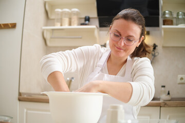 Smiling woman in the kitchen preparing a cake. Process of cooking pecan pie in home kitchen for American Thanksgiving Day.