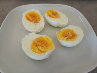Two boiled sliced eggs arranged on a white plate