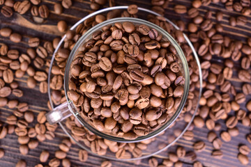 Cup of coffee full of coffee beans on a dark wooden background.Flat lei.

