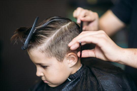 Little boy on a haircut in the barber sits on a chair