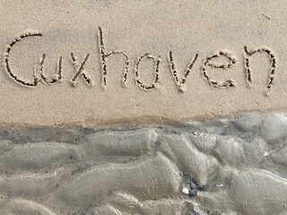 Schriftzug Cuxhaven am Strand der Nordsee an der Wattkante