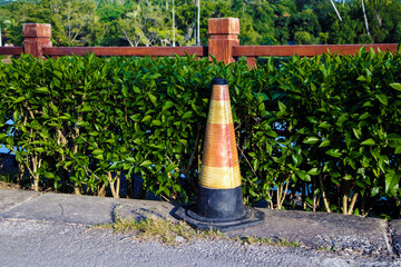 Fototapeta na wymiar dirty traffic cone, close-up of a recessed reflective traffic cone on a concrete surface, floor, white orange, red, old cone, green bushes background, park bokeh