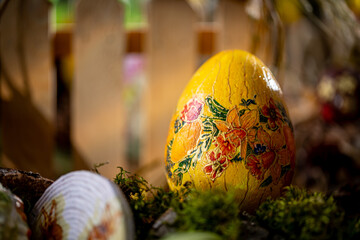 Springtime Easter Composition: Handcrafted Yellow Egg on Moss with Wooden Fence Background