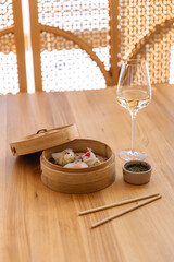 Chinese dumplings bottle of wine and sauce on table on wooden background in restaurant