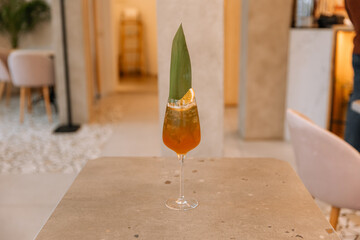 asian fizz cocktail with citrus and palm leaves on table in restaurant isolated on background